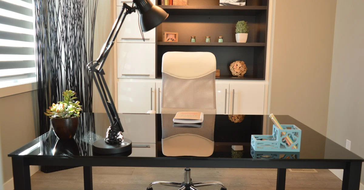 Stylischer moderner Büroarbeitsplatz mit einem schwarzen Schreibtisch, Lampe und einem weißen Stuhl mit Regalen.