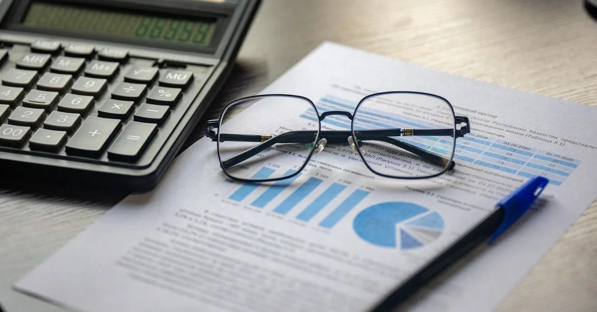 Finanzdokument mit einem Taschenrechner, Stift und Brille, die Datenanalyse symbolisieren.