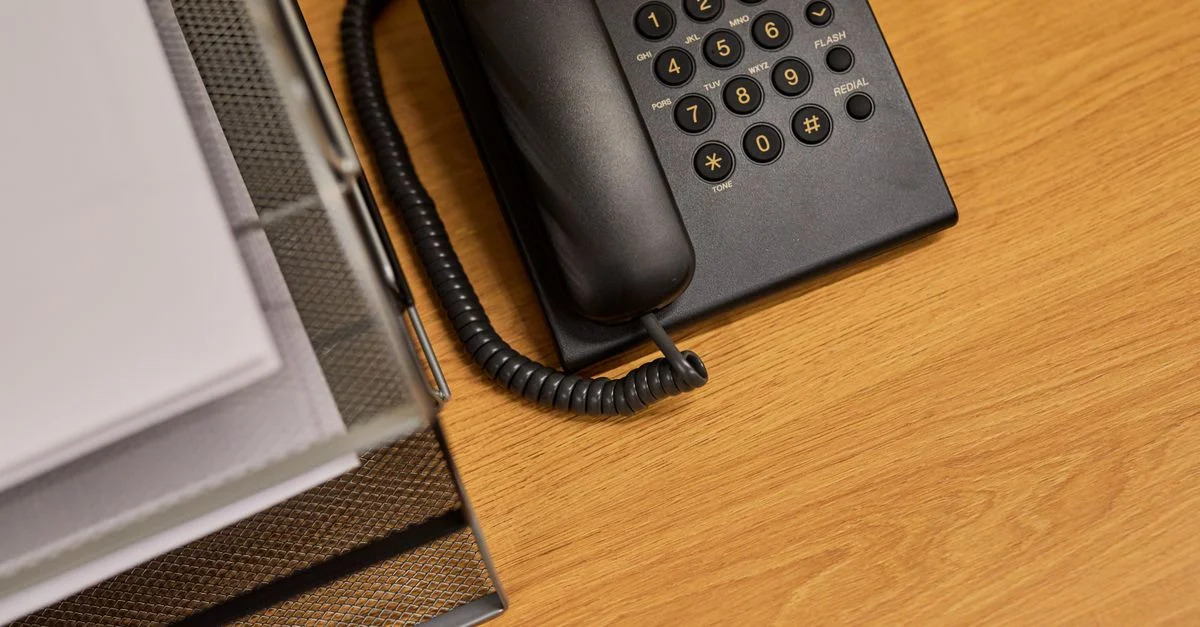 Ein ordentlicher Schreibtisch mit einem klassischen schwarzen Telefon und organisierten Dokumenten.