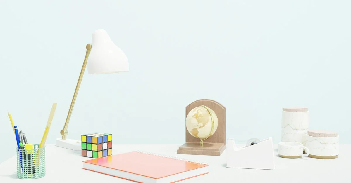 Ein sauberer und moderner Arbeitsplatz mit einer Lampe, einem Notizbuch, einem Globus und einem bunten Würfel.