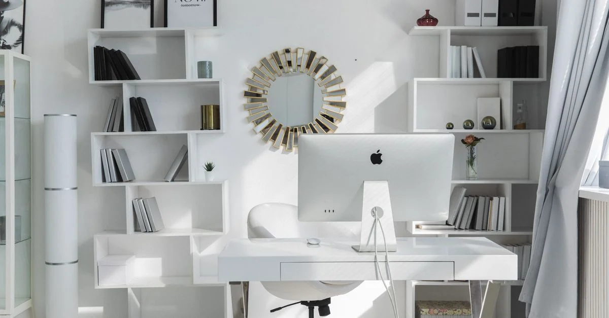 Helle, minimalistische Büroeinrichtung mit weißen Regalen, Schreibtisch und iMac. Ideal für Produktivität.