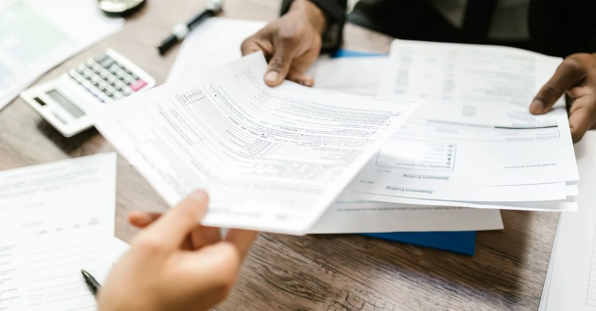 Zwei Fachleute tauschen Dokumente in einem Büroeinrichtung aus, mit Fokus auf Papierkram und Datenanalyse.