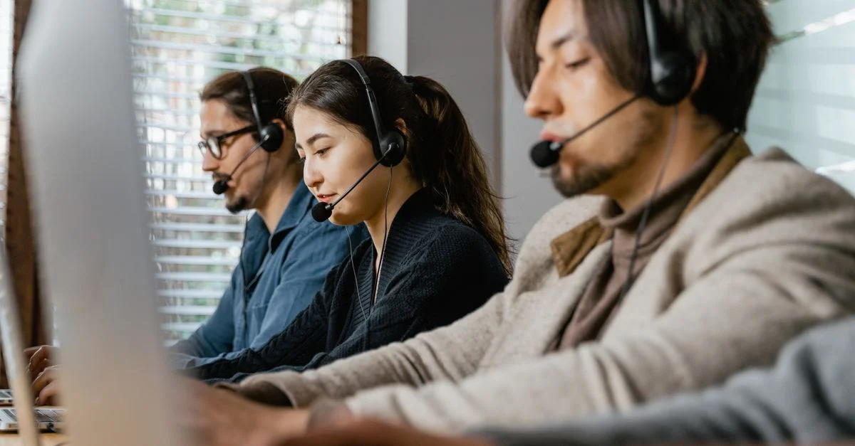Drei Call-Center-Agenten arbeiten fleißig mit Headsets in einem Büroumfeld und zeigen Teamarbeit.