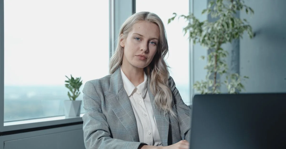 Professionelle Geschäftsfrau an einem Schreibtisch in einem hellen Büro mit Laptop und Notizbuch.